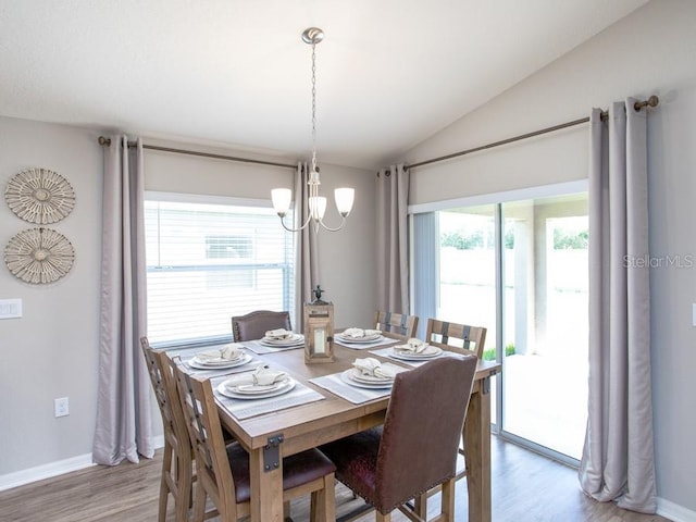 dining space featuring a chandelier, hardwood / wood-style floors, and vaulted ceiling