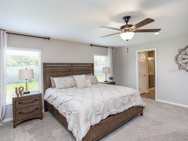 carpeted bedroom with ensuite bath and ceiling fan