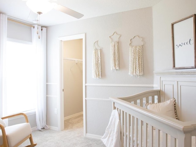 carpeted bedroom with a walk in closet, ceiling fan, and a closet