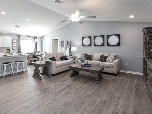 living room with ceiling fan, dark hardwood / wood-style flooring, lofted ceiling, and sink