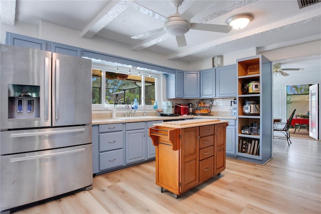 kitchen featuring sink, stainless steel fridge with ice dispenser, backsplash, light hardwood / wood-style floors, and a textured ceiling