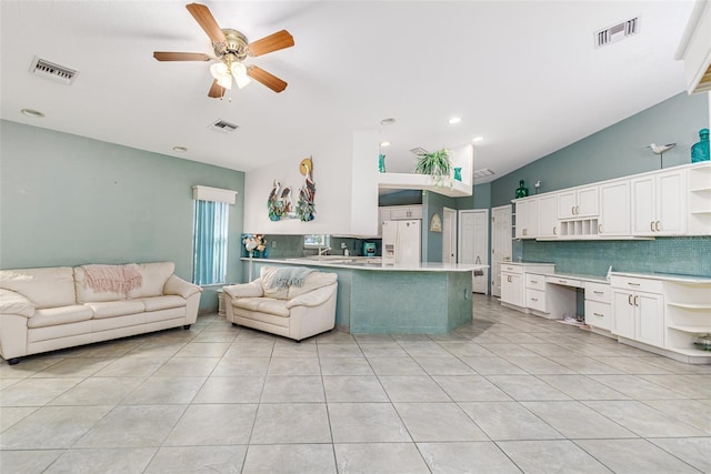 kitchen featuring white cabinets, decorative backsplash, ceiling fan, white fridge with ice dispenser, and kitchen peninsula