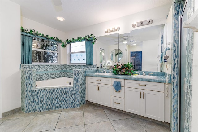 bathroom with tile patterned flooring, vanity, tiled bath, and ceiling fan