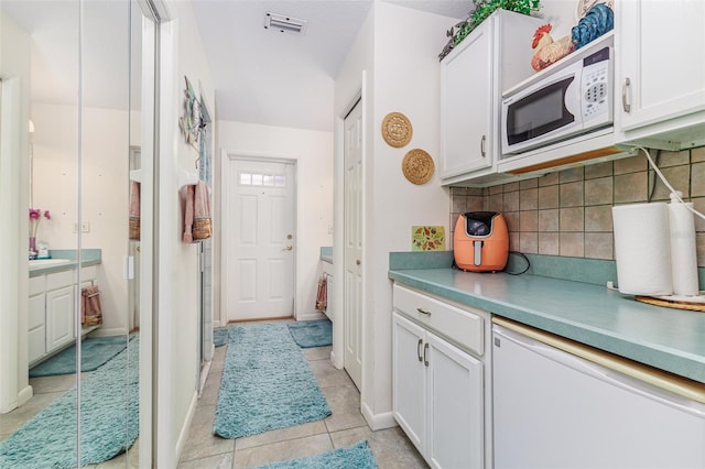 kitchen featuring light tile patterned floors, white cabinetry, and white microwave