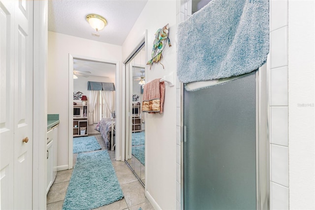 hall featuring light tile patterned flooring and a textured ceiling