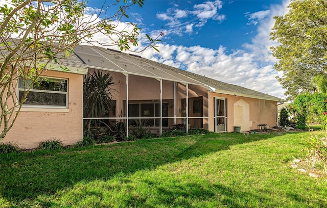 back of property featuring glass enclosure and a yard