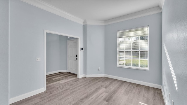 unfurnished room featuring a wealth of natural light, crown molding, and light wood-type flooring