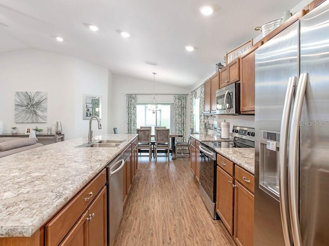 kitchen with sink, lofted ceiling, a kitchen island with sink, appliances with stainless steel finishes, and light wood-type flooring