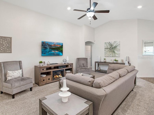 carpeted living room with ceiling fan and vaulted ceiling