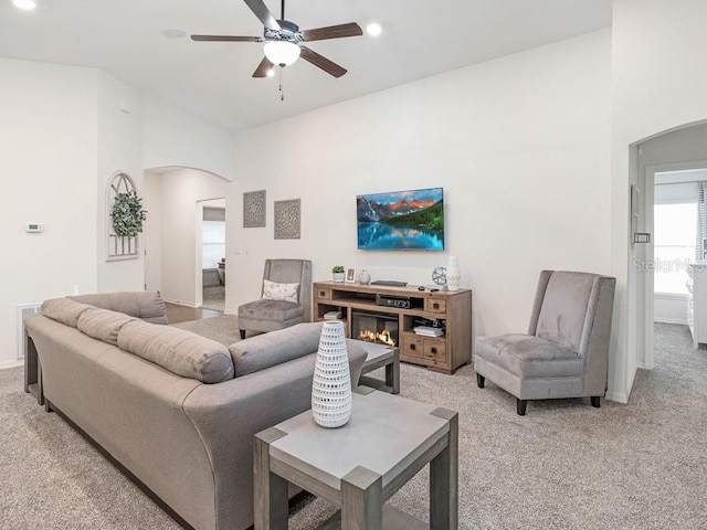 carpeted living room with a fireplace and ceiling fan