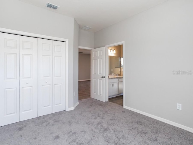 unfurnished bedroom with connected bathroom, light carpet, and a closet