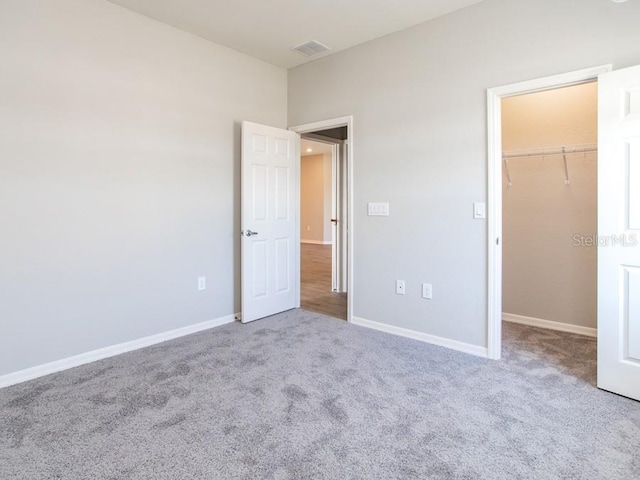 unfurnished bedroom featuring light colored carpet, a walk in closet, and a closet