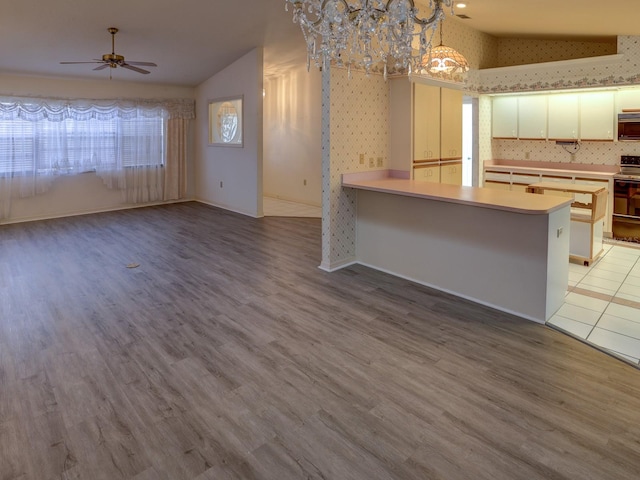 kitchen featuring pendant lighting, white cabinets, ceiling fan with notable chandelier, light hardwood / wood-style floors, and kitchen peninsula