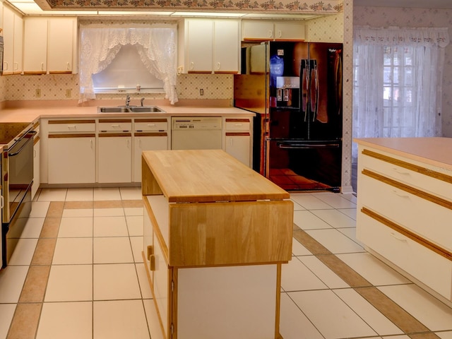 kitchen featuring light tile patterned flooring, sink, a center island, and black appliances