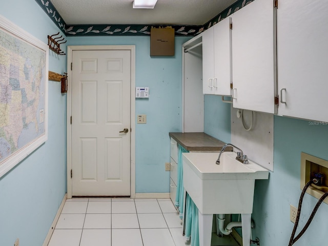 clothes washing area with washer hookup, cabinets, light tile patterned floors, and sink