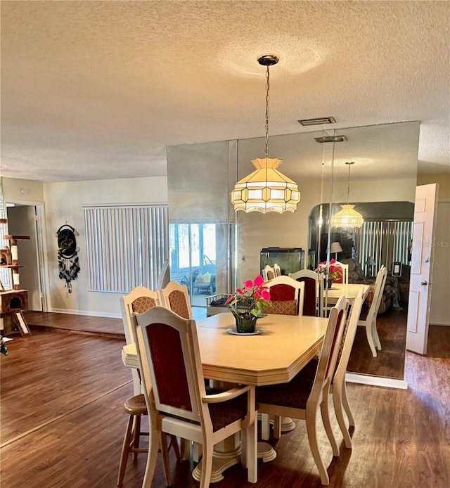 dining room with a textured ceiling, dark wood-style flooring, and visible vents