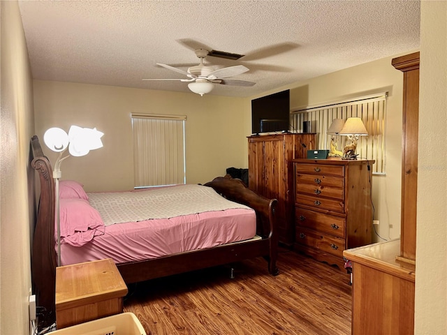 bedroom with a textured ceiling, ceiling fan, and wood finished floors