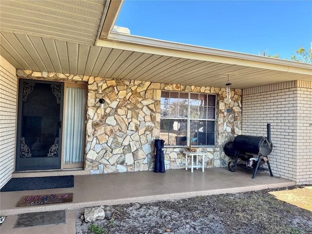 property entrance featuring covered porch and stone siding