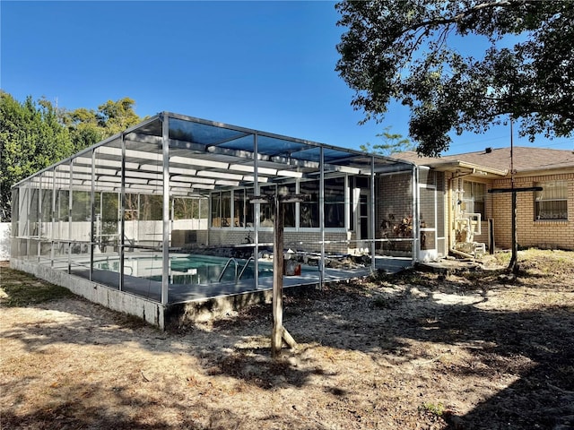 exterior space featuring glass enclosure, brick siding, and an outdoor pool