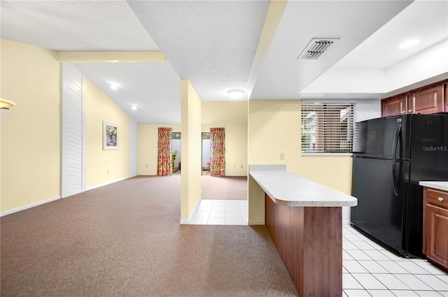 kitchen featuring light colored carpet, black fridge, and kitchen peninsula