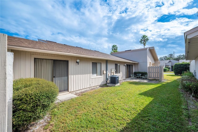 rear view of property with central AC and a lawn