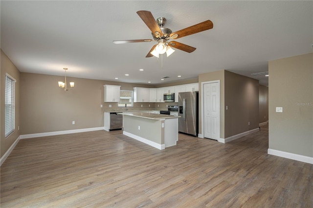 kitchen featuring stainless steel appliances, pendant lighting, light hardwood / wood-style flooring, white cabinets, and a kitchen island