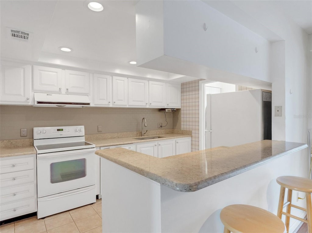 kitchen with a breakfast bar, white appliances, sink, exhaust hood, and white cabinetry