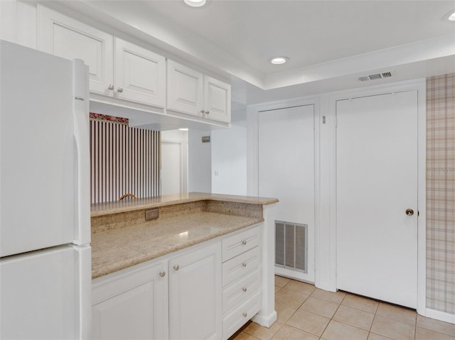 kitchen featuring light stone counters, ornamental molding, white refrigerator, white cabinets, and light tile patterned flooring