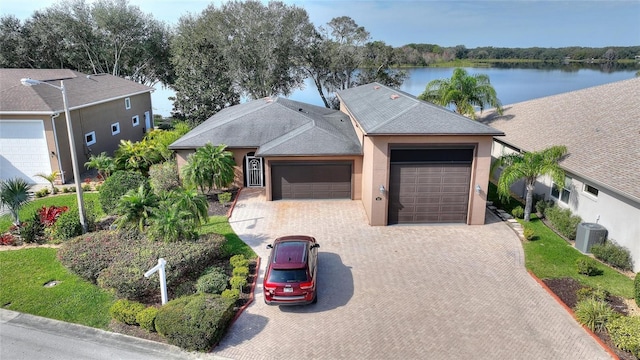 view of front facade featuring a garage, a water view, and central air condition unit