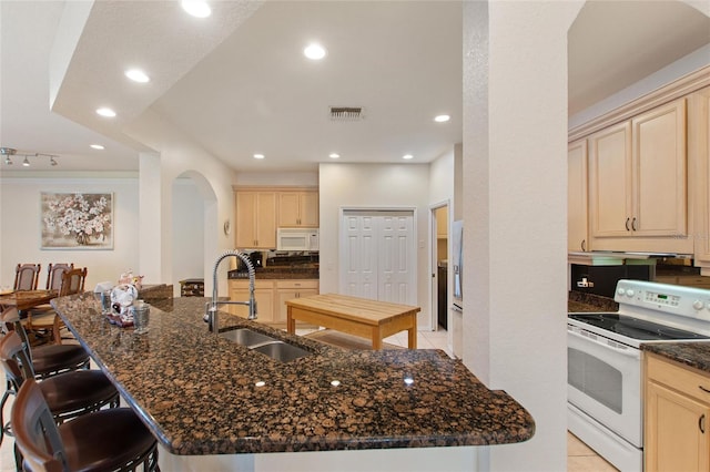 kitchen featuring a kitchen island with sink, sink, and white appliances