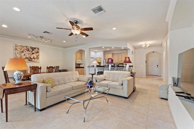 tiled living room featuring a textured ceiling, ornamental molding, and ceiling fan