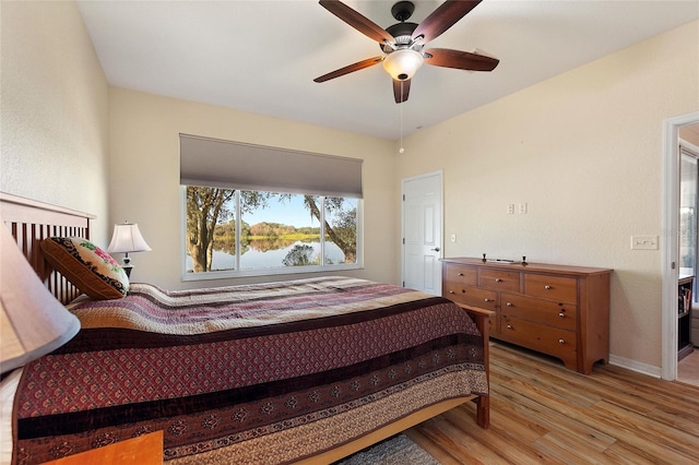 bedroom featuring a water view, ceiling fan, and light hardwood / wood-style flooring