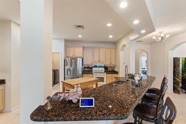 kitchen featuring washer / clothes dryer, sink, electric range, stainless steel refrigerator with ice dispenser, and light brown cabinets