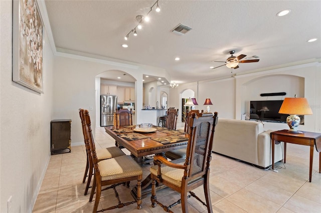 tiled dining space with ceiling fan, ornamental molding, and a textured ceiling