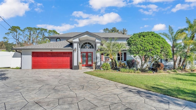 view of front of house with french doors, a garage, and a front lawn