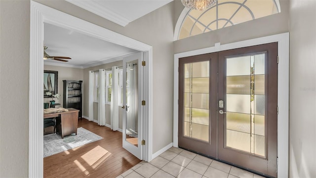 doorway featuring crown molding, a wealth of natural light, light hardwood / wood-style floors, and french doors