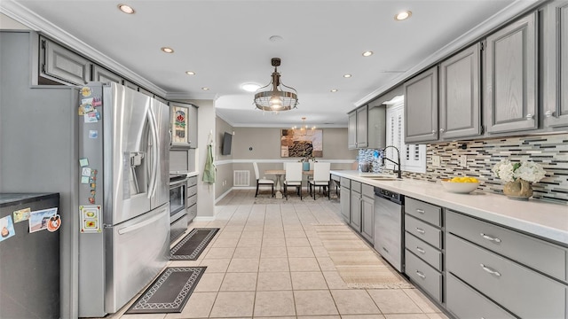 kitchen with sink, crown molding, stainless steel appliances, tasteful backsplash, and decorative light fixtures