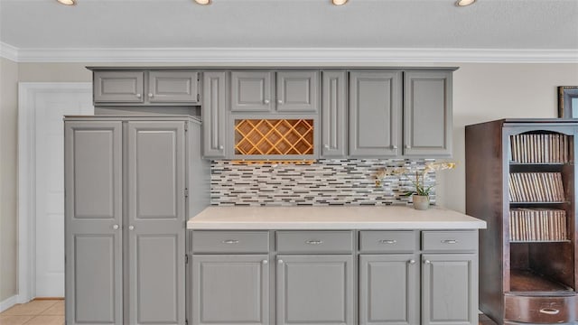 bar featuring gray cabinets, ornamental molding, light tile patterned floors, and backsplash