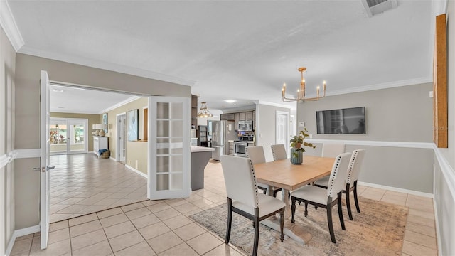 tiled dining area featuring crown molding, french doors, and a chandelier