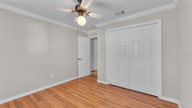 unfurnished bedroom featuring crown molding, light hardwood / wood-style floors, a closet, and ceiling fan