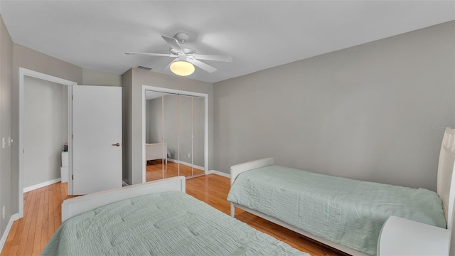 bedroom with wood-type flooring, ceiling fan, and a closet