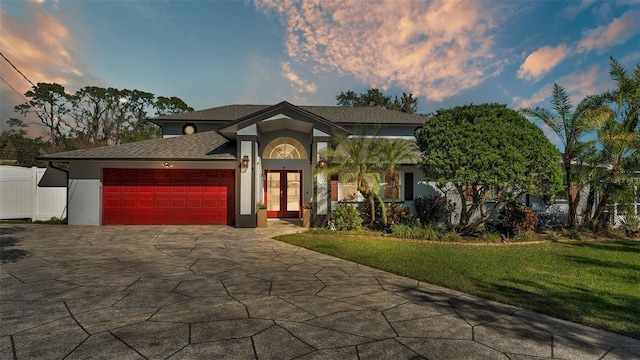 view of front of home with a garage, a lawn, and french doors