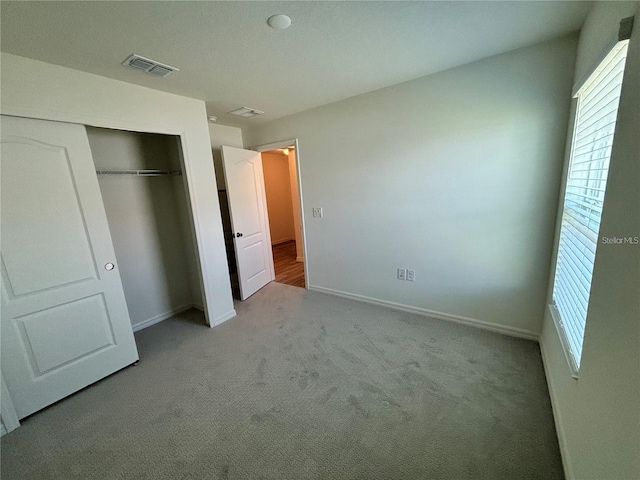 unfurnished bedroom featuring light carpet and a closet