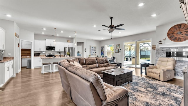 living room featuring a fireplace, hardwood / wood-style floors, ceiling fan, and sink