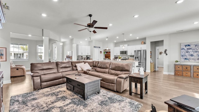 living room with light hardwood / wood-style flooring and ceiling fan