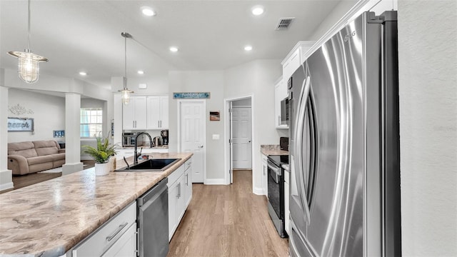 kitchen with white cabinets, pendant lighting, sink, and stainless steel appliances