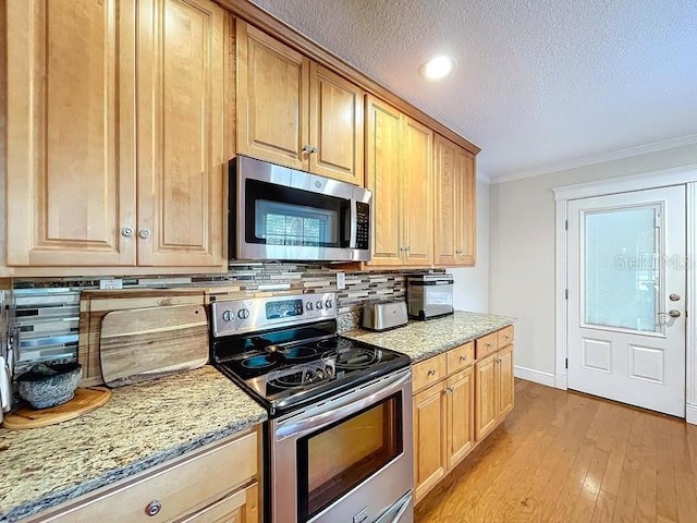 kitchen featuring tasteful backsplash, light stone counters, crown molding, and stainless steel appliances