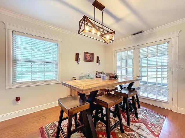 dining area with hardwood / wood-style floors and ornamental molding