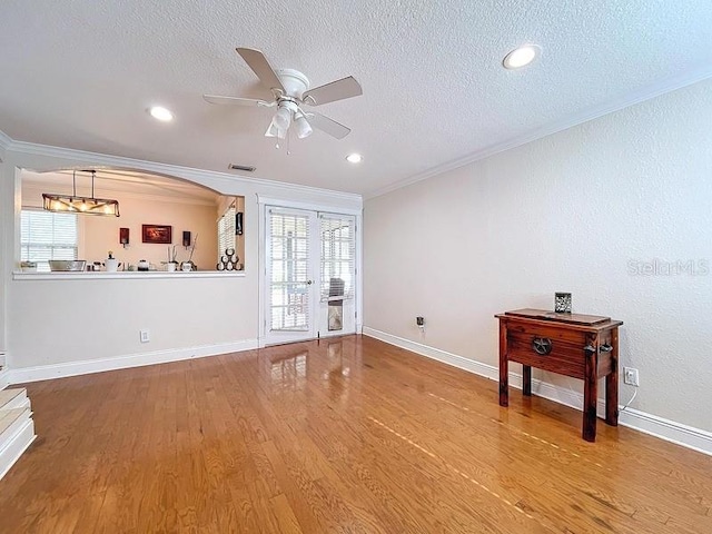 living room with ceiling fan, a healthy amount of sunlight, wood-type flooring, and crown molding