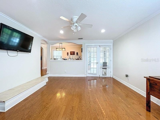 unfurnished living room with crown molding, ceiling fan, wood-type flooring, and a textured ceiling